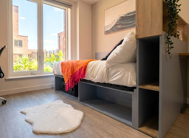 Side view of bed in Apex apartment with view out of window